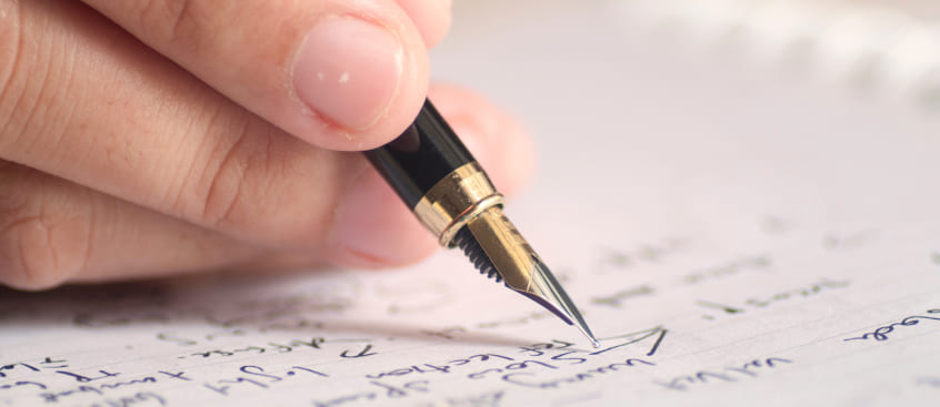 Mano que sostiene un lapicero y escribe en papel